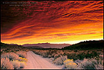 Picture: Alpenglow on storm clouds at sunrise over dirt road in the Eastern Sierra, near Bishop, California