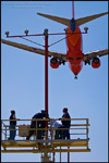 Picture: People  working on runway approach lights beneath  jet airplane landing at Los Angeles Int'l Airport LAX, California