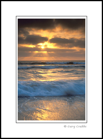 Sunset through coastal fog over ocean waves breaking on Torrey Pines State Beach, San Diego County Coast, California