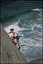 Picture: Female rock climber climbing over the ocean, Point Dume State Beach near Malibu, California