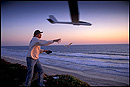 Picture: Launching a radio-controlled glider into the wind, over the ocean at sunset, Carlsbad, California