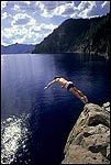 Photo: Tourist taking a dive off rock cliff into clear blue water of Crater Lake at Cleetwood Cove, Crater Lake National Park, Oregon
