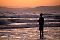 Young man surf fishing at sunset, Morro Strand State Beach, Central Coast, California