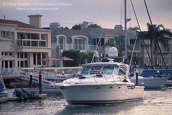 Luxury yacht Boat cruising through harbor channel next to waterfront homes at Newport Beach, California