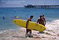 Lifeguard carries a surfboard on beach near Balboa Pier, Balboa Island, Newport Beach, California