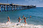 Young girls run into ocean water from sand beach at Balboa Pier, Balboa Island, Newport Beach, California