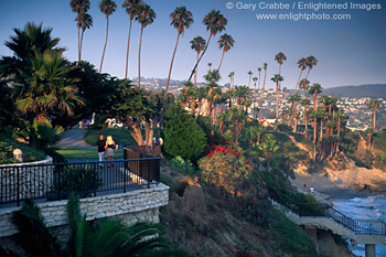 Sunset light along palm tree lined promenade and coastal cliffs at Heisler Park, Laguna Beach, Orange County, California