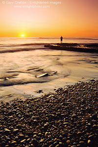 Person standing on pebble beach at sunset, Swami'a Beach, Encinitas, San Diego County Coast, California