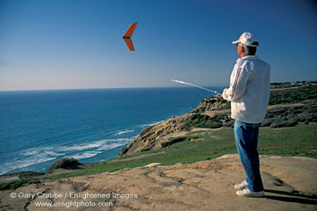 Man flying radio contolled glider from bluff overlooking the Pacific Ocean, near La Jolla, San Diego County Coast, California