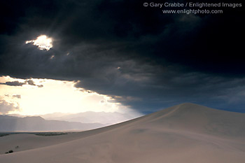 Sunlight and dark storm clouds over desert sand dune, near Stovepipe Wells, Death Valley National Park, California; Stock Photo photography picture image photograph fine art decor print wall mural gallery