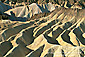 Golden yellow eroded ridges and erosion gullies on barren hills near Zabriskie Point, Death Valley National Park, California