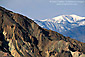 Snow-capped mountain and barren eroded hills, Death Valley National Park, California
