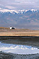Truck towing RV Camper trailer below mountains reflected in spring water pool at Badwater, Death Valley National Park, California