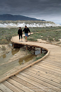 Tourist Couple on boardwalk pathway at Salt Creek Natural Area, Death Valley National Park, California; Stock Photo image picture photo Phograph art decor print wall mural gallery