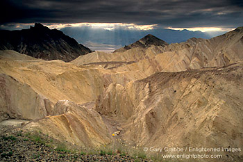 Sunbeams and dark storm clouds over eroded hills in Golden Canyon, Death Valley National Park, California; Stock Photo image picture photo Phograph art decor print wall mural gallery