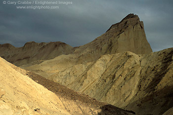 Sunlight on barren hills below storm clouds and Zabriskie Point, Golden Canyon, Death Valley National Park, California; Stock Photo image picture photo Phograph art decor print wall mural gallery