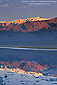 Mountains reflected at sunrise in flooded waters of desert basin, Death Valley National Park, California