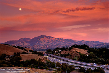 Full moon rising through red clouds during a stormy sunset over Mount Diablo, Lafayette, Contra Costa County, San Francisco Bay Area, California