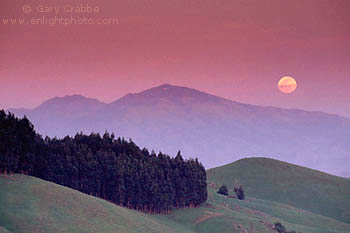 Full moon rising at sunset over green hills in spring and Mount Diablo, from the Orinda Hills, Contra Costa County, San Francisco Bay Area, California