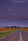 Full moon rising in evening sky over rural road next to vineyards in the Carneros Region, Napa County, California