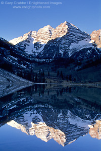 Sunrise light on snow covered mountains reflected in alpine lake on a clear morning, Maroon Bells Wilderness, near Aspen, Rocky Mountains, Colorado