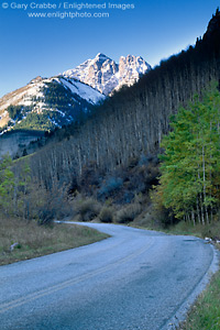 Snow covered mountain peak over twisting mountain road and aspen trees, Maroon Bells Wilderness, near Aspen, Rocky Mountains, Colorado