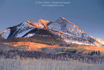 Aspen trees and mountain peak at sunset after first snow fall of the season, near McClure Pass, Rocky Mountains, Colorado