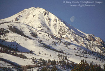 Moonset over snow-covered mountain in winter near Conway Summit, Eastern Sierra, California