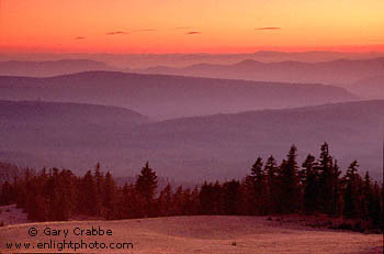 Sunset over trees and forested rolling hills, from the rim of Crater Lake, Crater Lake National Park, Oregon