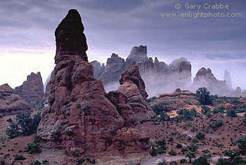 Mist shrouds red rock formations after a fall rainstorm, Arches National Park, Utah