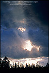 Picture: Sunbeams at sunrise through hole in dark storm clouds over trees, Grand Teton National Park, WYOMING