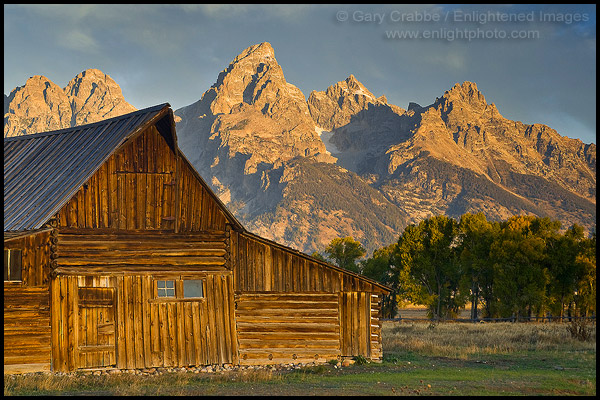 Photo: Sunrise light on the Grand Teton mountain peak over old wooden barn, Mormon Row, Grand Teton National Park, Wyoming